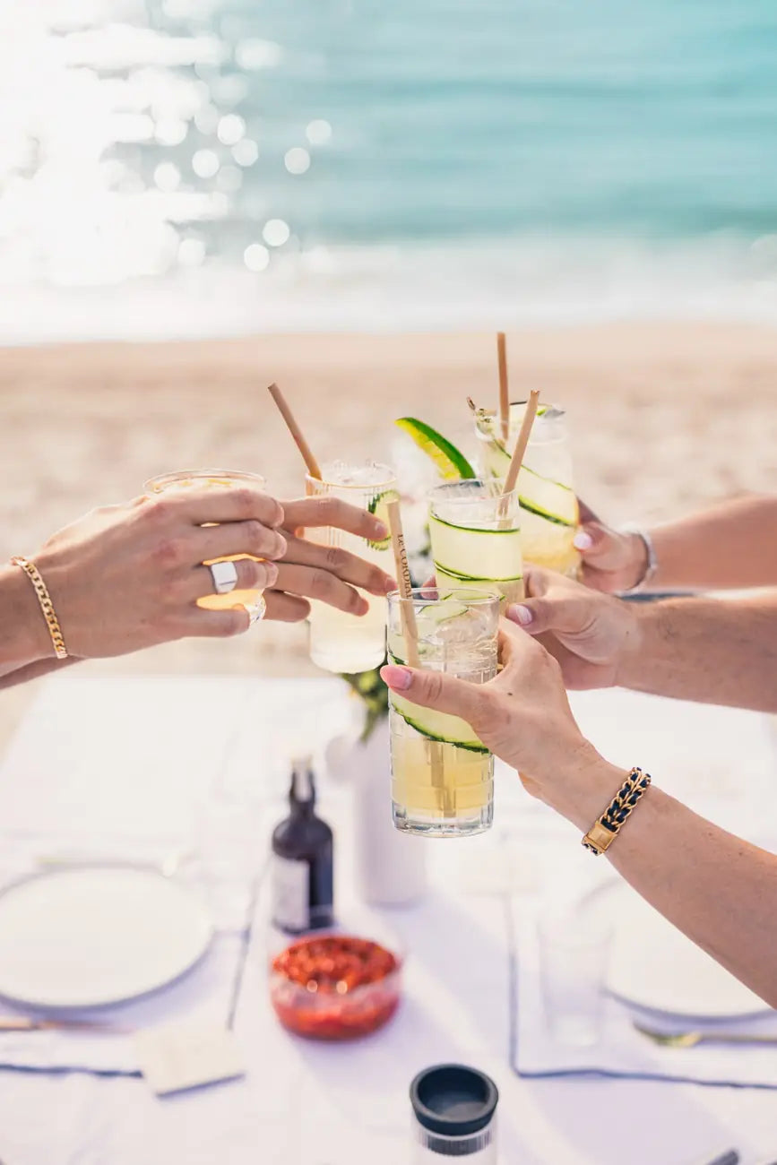 Des amis trinquent avec des cocktails au cordial au bord de la mer